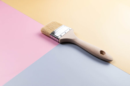 Top view of paint brush on colourful background. Blue, pink and yellow background. Colourful...