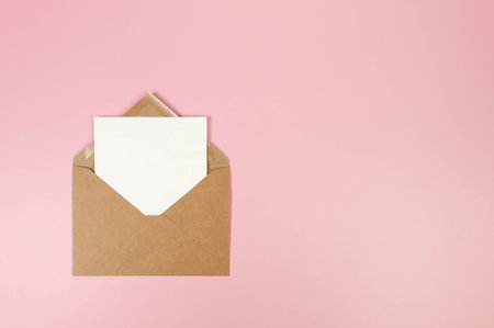 Top view of brown kraft envelope, white card on pink background. Post flat lay. Copy space.の写真素材