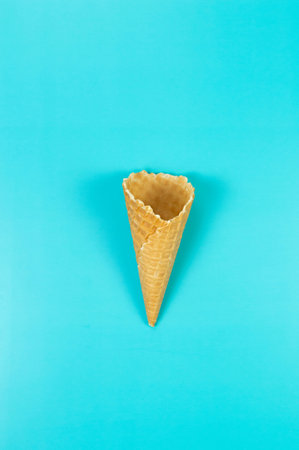 Top view of ice cream waffle cone on blue background. Summer wallpaper, flat lay, copy space.の写真素材