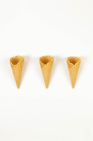 Top view of three ice cream waffle cones on white background. Summer wallpaper, flat lay, copy space.の写真素材