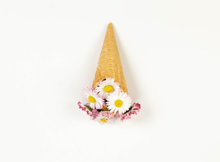 Top view of daisy flowers bouquet on white background. Creative ice cream waffle cone. Spring and summer wallpaper, flat lay, copy space.の写真素材