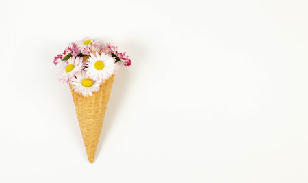 Top view of daisy flowers bouquet on white background. Creative ice cream waffle cone. Spring and summer wallpaper, flat lay, copy space.の写真素材