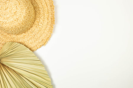 Top view of straw hat and dried palm leaf on white background. Summer fashion, vacation and beach wallpaper. Copy space, flat lay.の写真素材