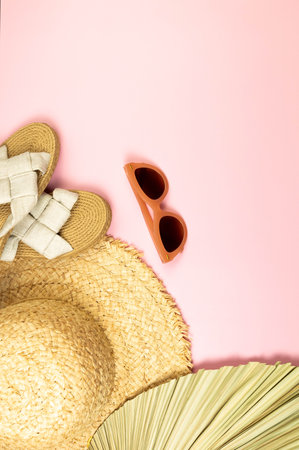 Top view of straw hat, dried palm leaf, slippers and sunglass on pink background. Summer fashion, vacation and beach wallpaper. Copy space, flat lay.の写真素材