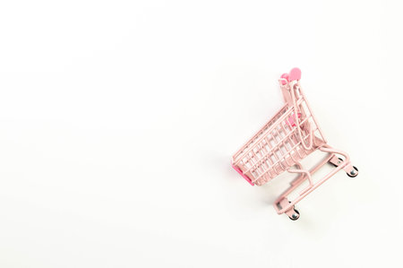 Top view of pink shopping trolley on white background. Creative shopping wallpaper, sale. Copy space, flat lay.の写真素材