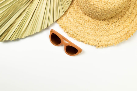 Top view of straw hat, dried palm leaf and sunglass on white background. Summer fashion, vacation and beach wallpaper. Copy space, flat lay.の写真素材
