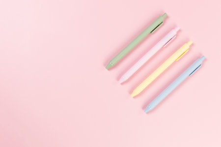 Top view of colorful pens on pink background. School, office wallpaper. Flat lay, copy space.