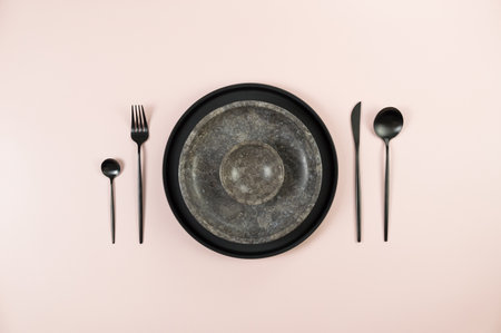 Top view of brown marble plate and bowl, black plate and cutlery on pink background. Food presentation, stone tray. Table setting, copy space, flat lay.の写真素材
