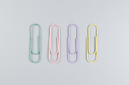 Top view of colorful paperclips on grey background. School, office wallpaper. Flat lay, copy space.の写真素材
