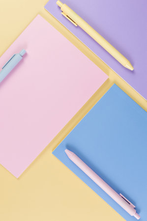 Top view of pink, purple and blue notebooks on yellow background. Pink, yellow and blue pens, school, office wallpaper. Flat lay, copy space.の写真素材