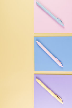 Top view of pink, purple and blue notebooks on yellow background. Pink, yellow and blue pens, school, office wallpaper. Flat lay, copy space.の写真素材