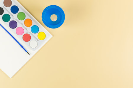 Top view of watercolor, paper, water pot and paint brush on yellow background. Painting, art, copy space, flat lay.の写真素材