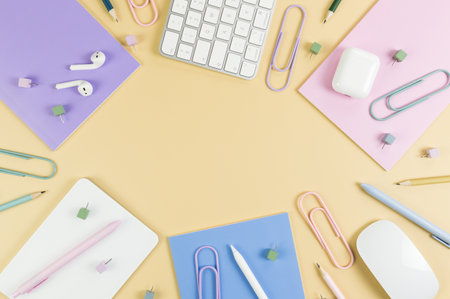 Top view of white keyboard, mouse, touchpad, earphones case, pen on yellow background. Purple, pink...