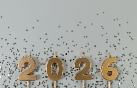 2026 Happy New Year. Top view of gold numbers, silver stars confetti on grey background. Copy space,...