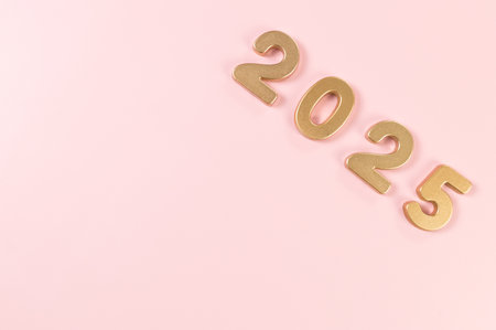 2025 Happy New Year. Top view of gold numbers on pink background. Copy space, flat lay.の写真素材