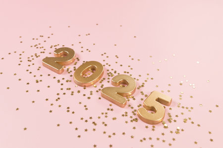 2025 Happy New Year. Top view of gold numbers, gold stars confetti on pink background. Copy space, flat lay.の写真素材