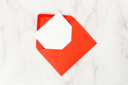 Top view of red envelope, white card on white marble background. Post flat lay. Copy space.の写真素材