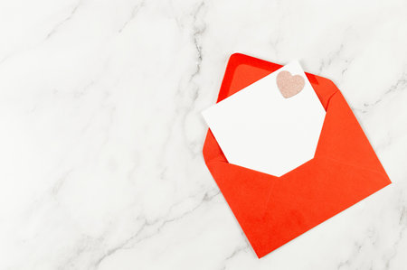 Top view of red envelope, white card on white marble background. Valentine's day, pink glitter heart, love. Post flat lay, copy space.の写真素材