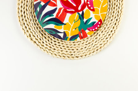 Top view of brown wicker table mat, colorful plate on white background. Straw round tray, exotic plant plate, summer picnic. Flat lay, copy space.の写真素材