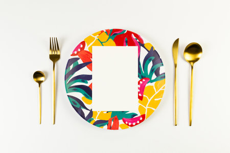 Top view of colorful plate, white card, gold cutlery on white background. Exotic plant plate, summer...