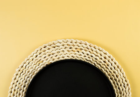 Top view of brown wicker table mat, black plate on yellow background. Flat lay, copy space.の写真素材