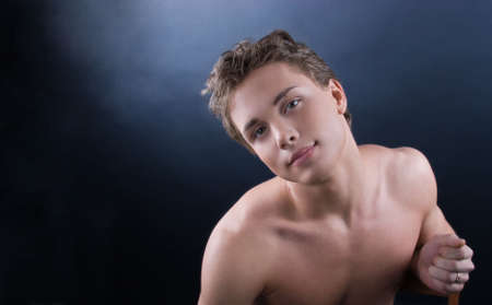 Young man posing against dark bakgroundの写真素材