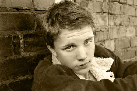 Portrait of the young and pretty boy sitting near the grunge wallの写真素材