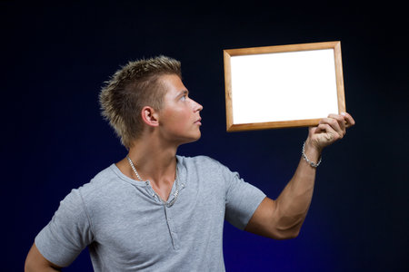 Handsome young muscular man with empty wooden frame.