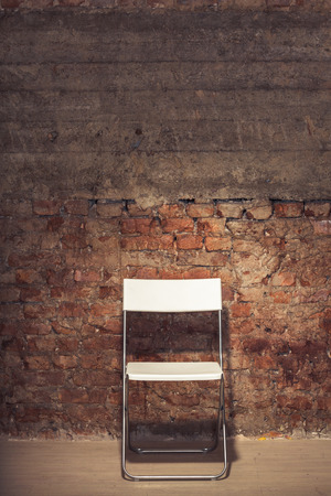 Simple folding-chair near the grungy brick wallの写真素材