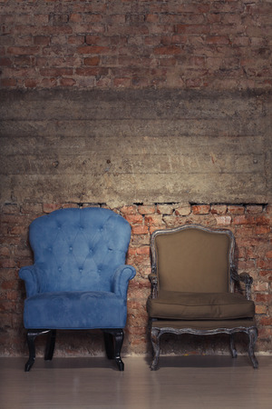 Two antique chairs against a grungy brick wallの写真素材