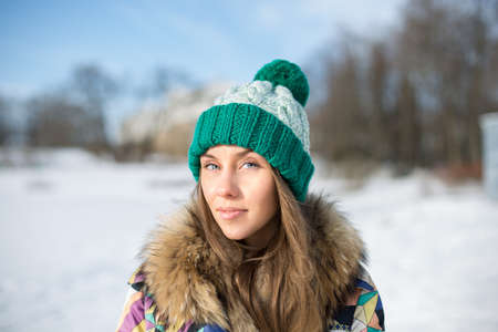 Beautiful young woman in bright knitted cap in winter parkの写真素材