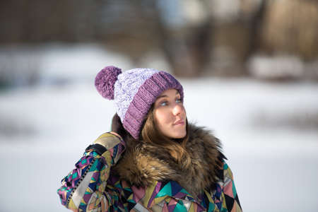 Beautiful young woman in bright knitted cap in winter parkの写真素材
