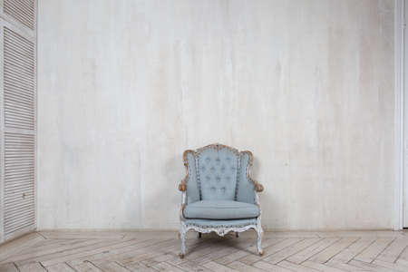 Old antique armchair furniture against light grey grungy wall. Abstract empty roomの写真素材