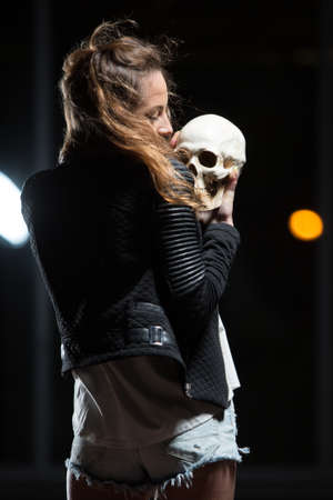 Young beautiful woman holding human skull outdoorsの写真素材