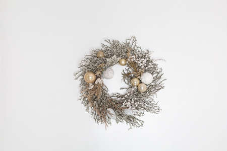 Christmas wreath on the light wall. White and gold colors