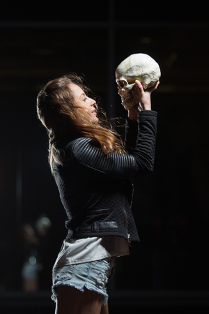 Young beautiful woman holding human skull outdoors at nightの写真素材