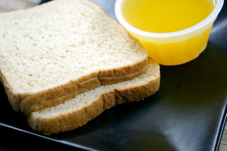 bread and orange juice on dishの写真素材