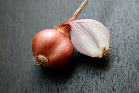 Sliced shallot with whole shallots on black woodの写真素材