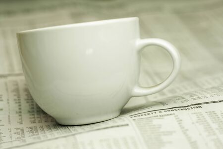 cup of coffee and the newspaper with a very shallow depth of field with copy space for textの写真素材