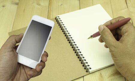 hand holding the smartphone on book background