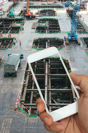 hand holding the smartphone on construction site background