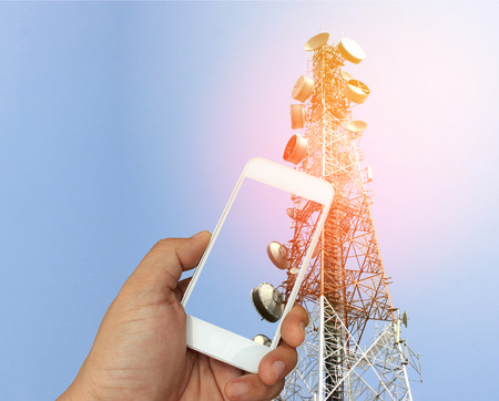 hand holding the smartphone on telecommunication radio antenna background with burst lightの写真素材