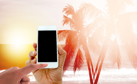 hand hold and touch screen smart phone on coconut palm trees with burst lightの写真素材