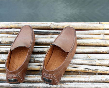 Brown shoe on bamboo wood over pond