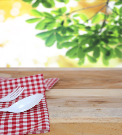 spoon with fork on checkered tablecloth and blur leaves backgroundの写真素材