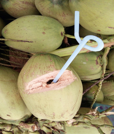 Sweet green coconuts water with drinking straw の写真素材
