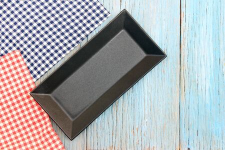 black plate on tablecloth on wood table background
