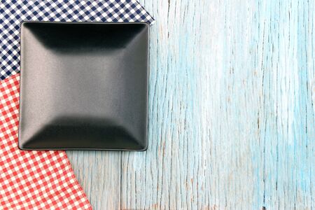 black plate on tablecloth on wood table background