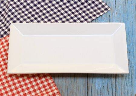 white plate on tablecloth on wood table background