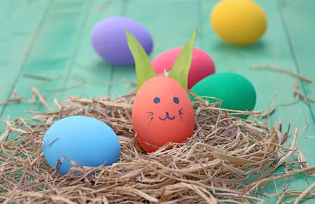straw basket with easter eggs on wooden background